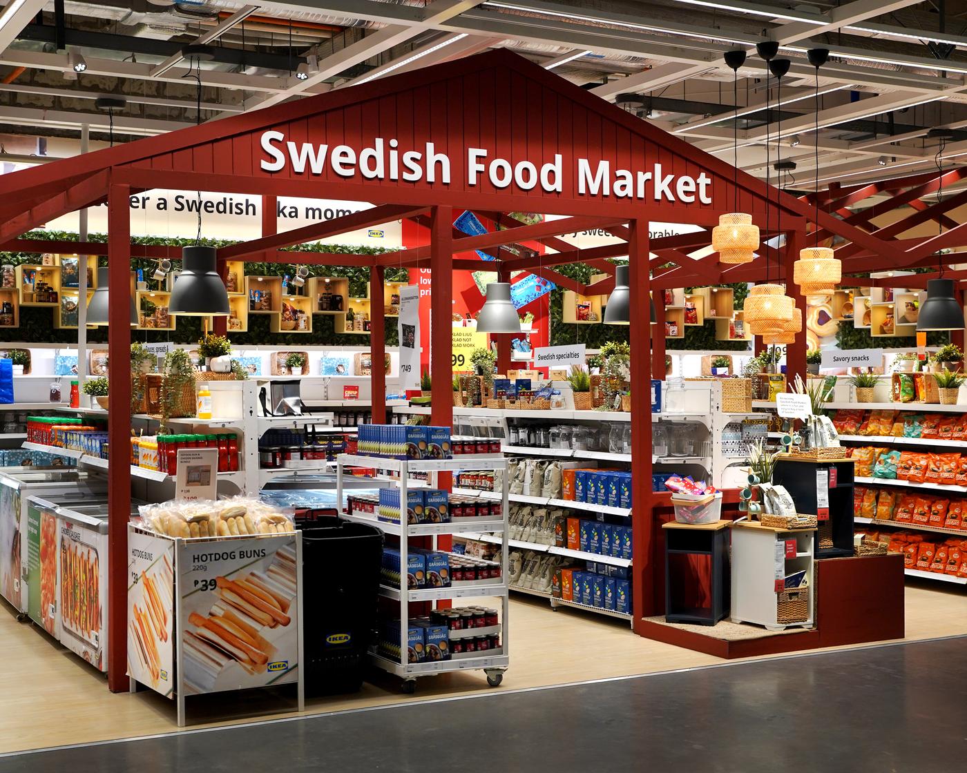 Alt text: "A vibrant Swedish Food Market with red wooden beams and shelving. It features colorful packages, baskets, hanging lamps, and signs with food items."