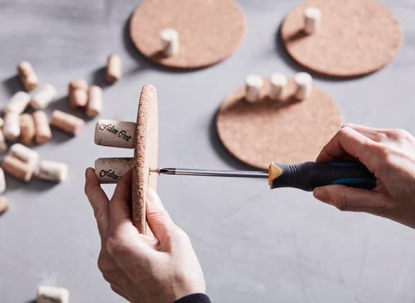 Alte Flaschenkorken werden in Topfuntersetzer aus Kork geschraubt und an einer Wand als Aufbewahrung verwendet