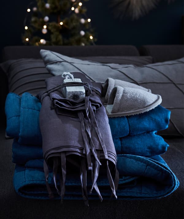 Alu-alukan tetamu dengan selipar baharu dan sarung bantal dan sarung kuilt IKEA PUDERVIVA dalam linen rapi.