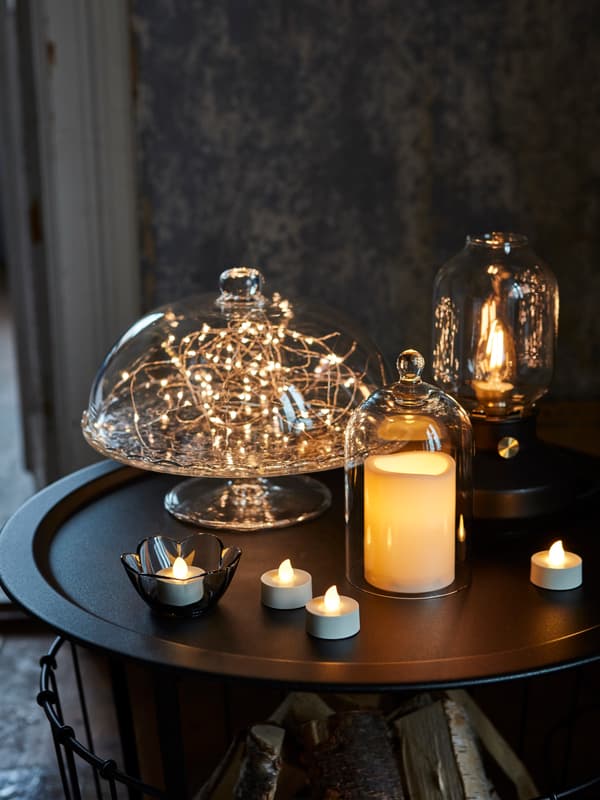 Ambient tabletop lighting setup with candles and decorative string lights enclosed in glass domes, creating a warm and cozy glow.