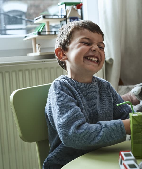 Amélie’s son Noah sits laughing at a table.