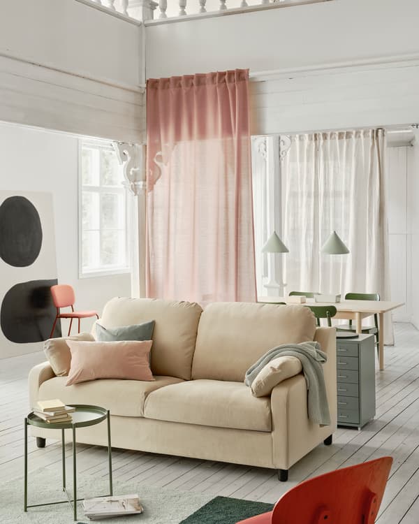 Amplio sofá VINLIDEN de color beige en una sala de estar con una alfombra y una mesa pequeña en primer plano.