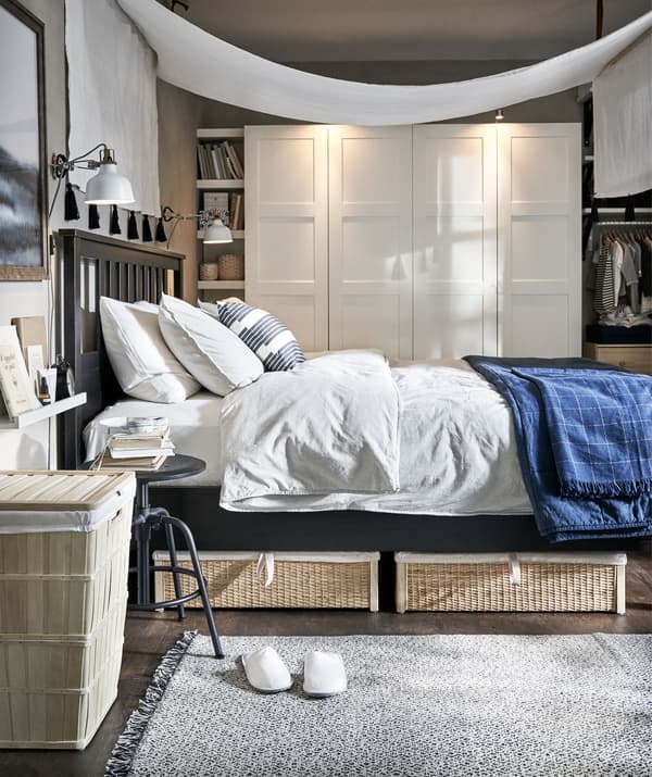 Amplo dormitorio con materiais naturais e un dosel sobre a cama. Armario na parede do fondo.