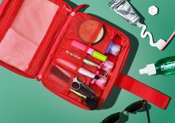 An accessory bag containing makeup and toilettries is laid open and shot from above.