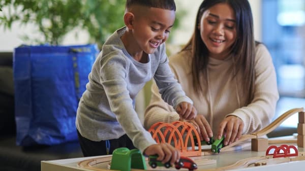 an adult and child playing with IKEA toy trains