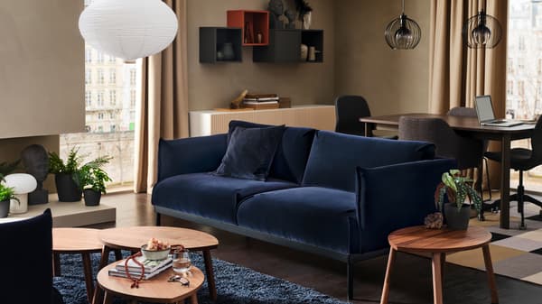An ÄPPLARYD sofa with three coffee tables in front on a blue high pile rug. A dining table and chairs is behind the sofa.