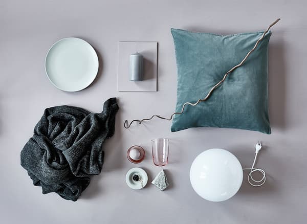 An aerial view of a cushion, blanket, lamp, and natural elements for autumn decoration.