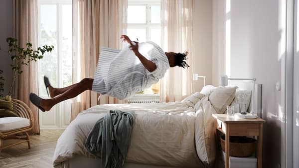 An aerial view of a person asleep on their back on a bed, partially covered by a beige KRITSUGA duvet cover with pillowcase.