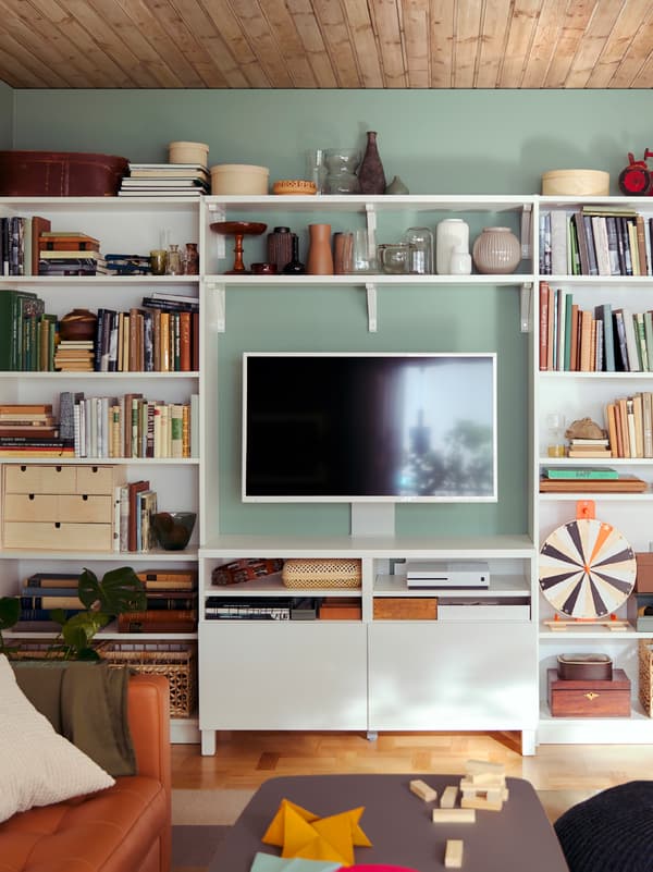 An all-inclusive, living-room storage wall formed by a combination of BILLY bookcases and BERGSHULT/SANDSHULT shelves.