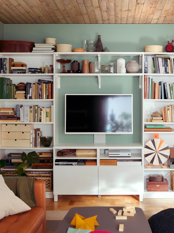 An all-inclusive, living-room storage wall formed by a combination of BILLY bookcases and BERGSHULT/SANDSHULT shelves.