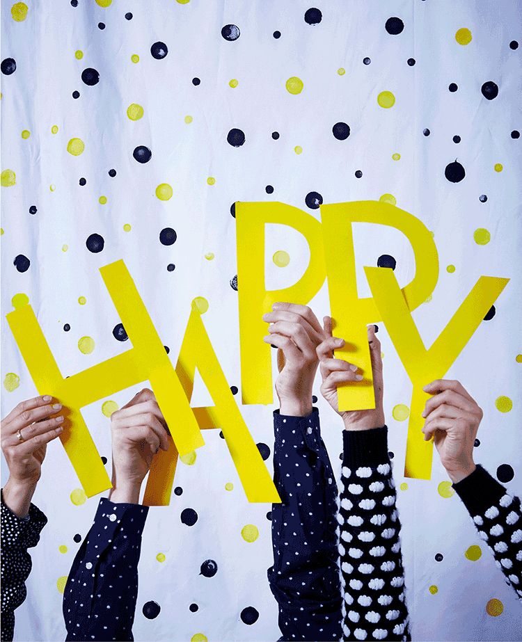 An animated GIF showing people wearing polka dot clothes holding up yellow letters that spell 'Happy New Year.'