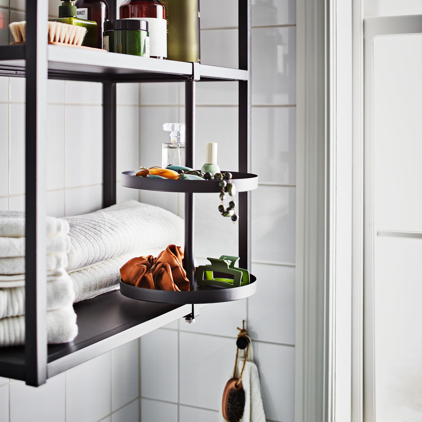 An anthracite ENHET wall frame with shelves with white folded towels, with a swivel shelf in the same series mounted on it.