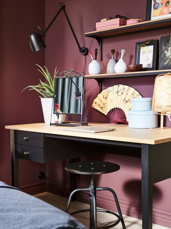 An ARKELSTORP desk in black and solid pine, a black wall lamp, a table lamp in bamboo and a black stool.