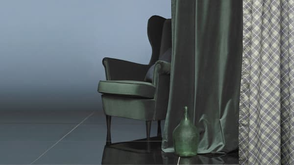 An armchair behind a curtain in matching dark green velvet.