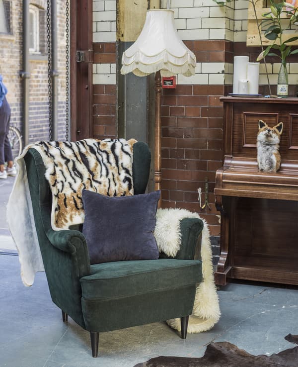 An armchair, cushion and throw in an industrial space.
