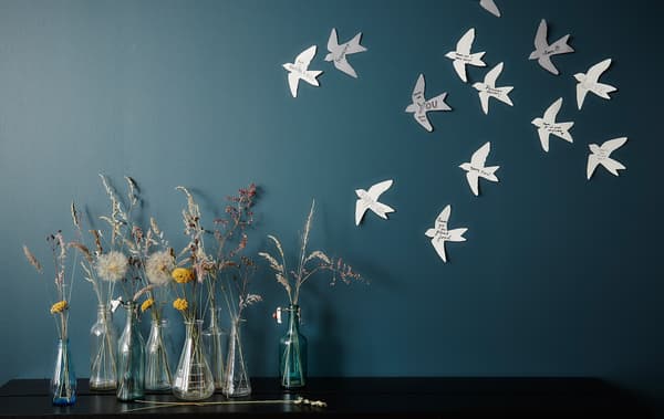 An arrangement of vases next to a wall with paper birds.