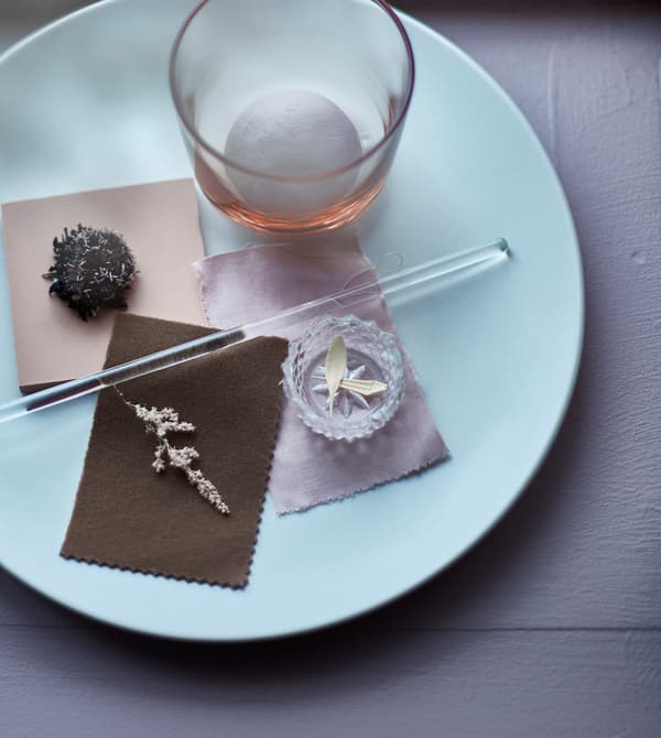 An arrangement on a plate with small flowers and textile pieces.