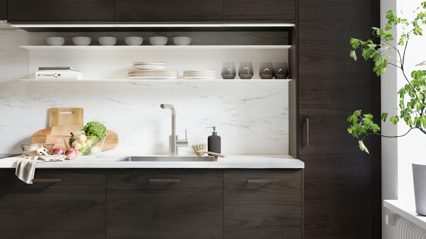 An ASKERSUND kitchen in dark drown ash effect with chopping boards and vegetables on an EKBACKEN worktop in marble effect.