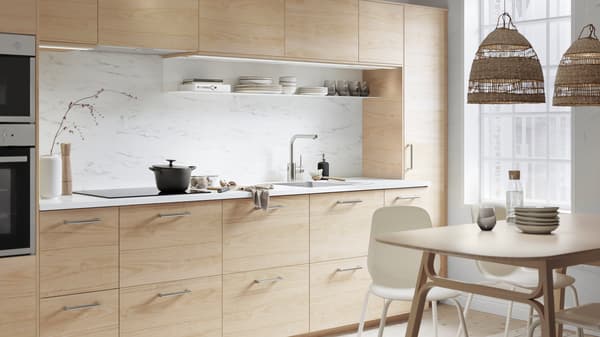 An ASKERSUND kitchen in light-ash effect with an EKBACKEN worktop in white marble effect. There is a casserole on the hob.