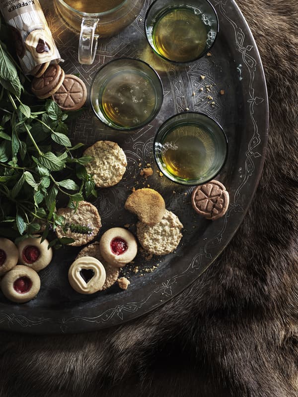 An assortment of cookies and cups of tea arranged on a large tray.