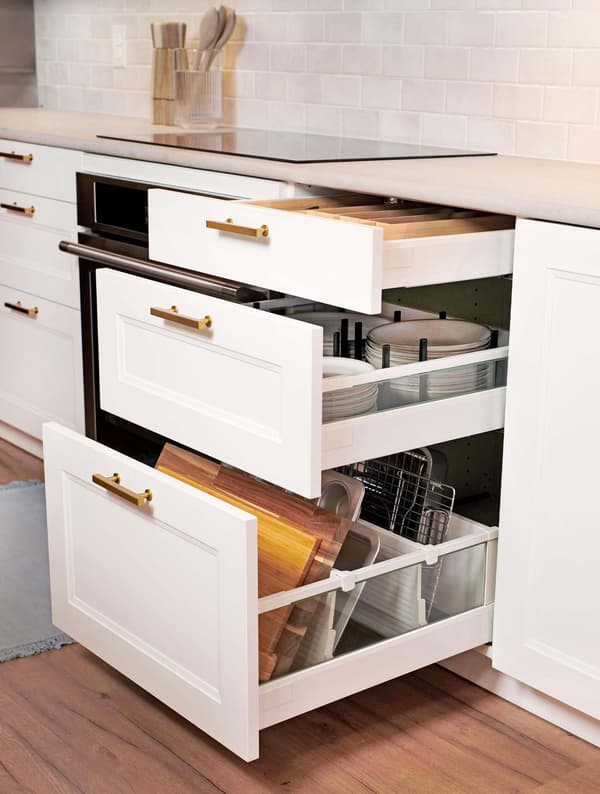 An AXSTAD kitchen with matte white fronts features two base cabinets, a tall wall cabinet, black appliances and a brown rug.