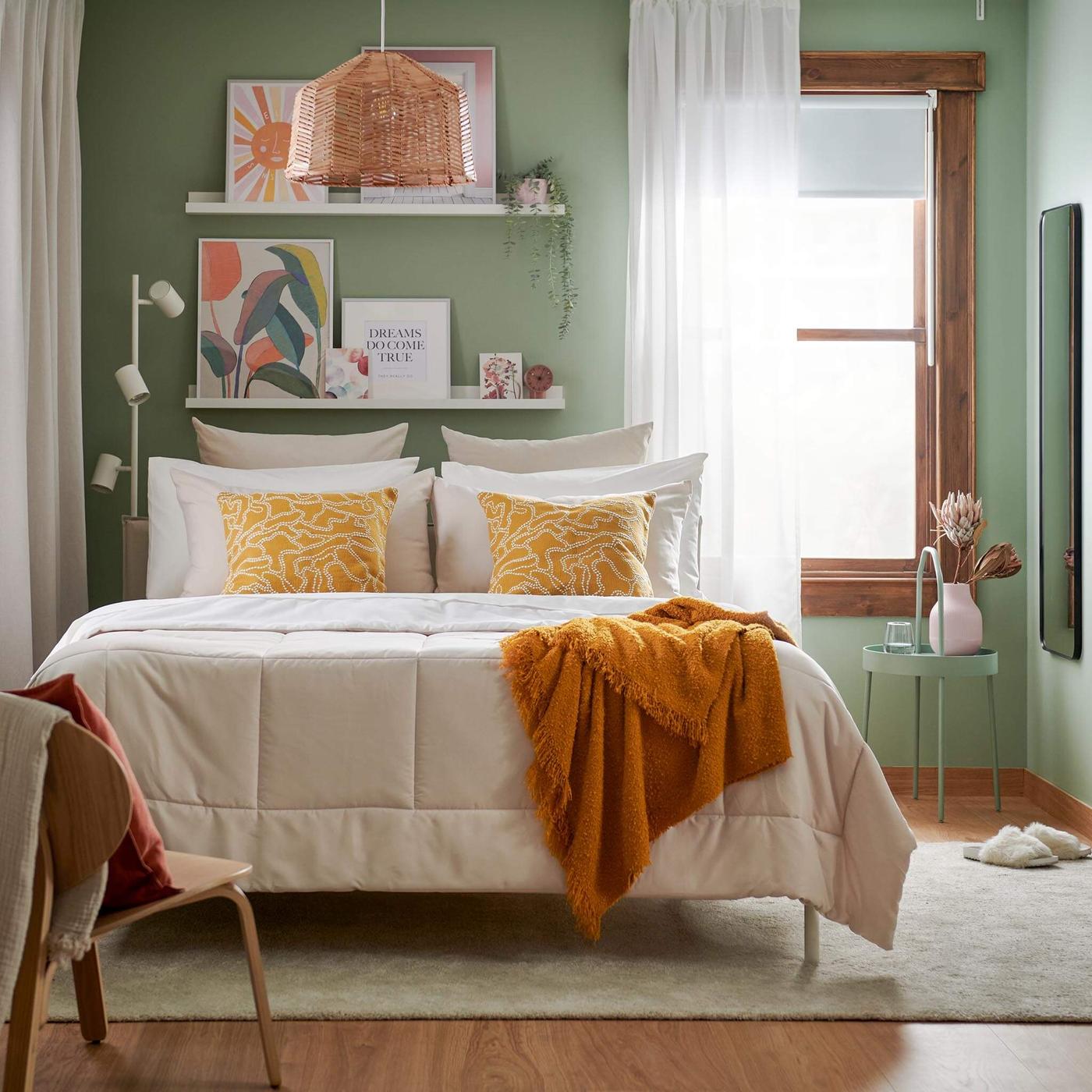 An earthy toned bedroom with an orange throw blanket and a beige comforter.
