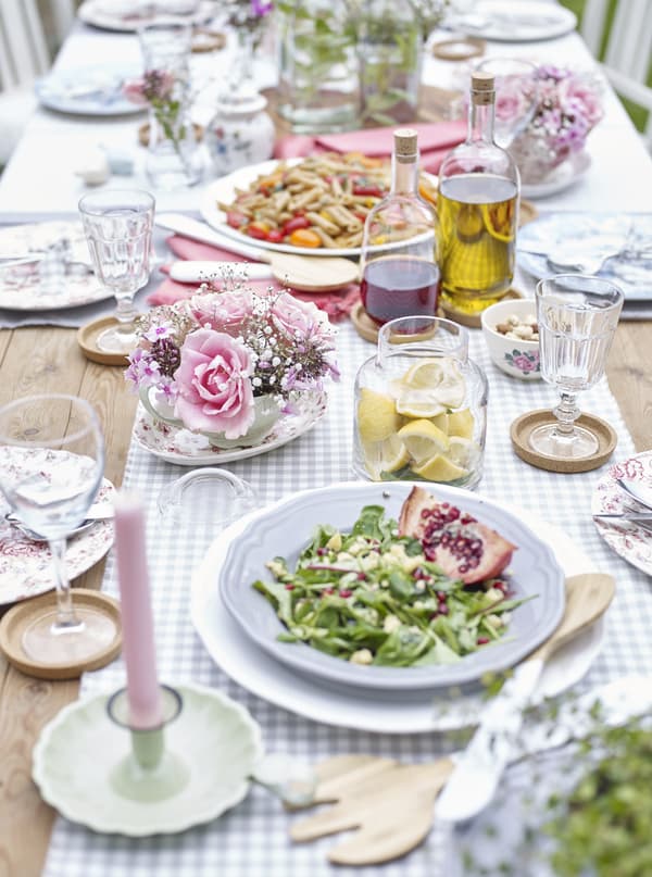 An eclectic table laid for outdoor dining. Colourful food served on white tableware.