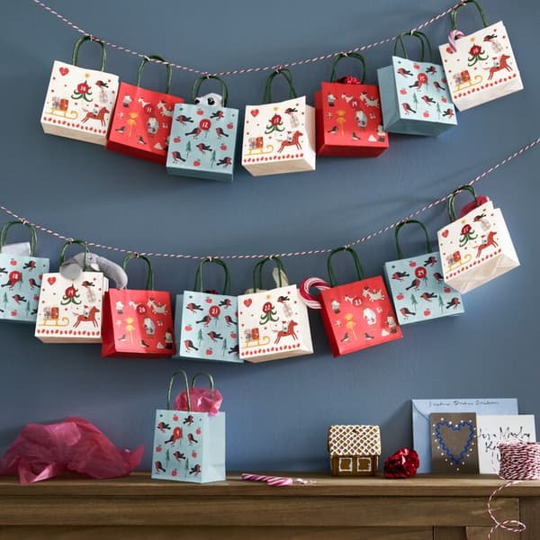 An einer blauen Wand hängen selbstgemachte Geschenke in weiß, rot und blau.