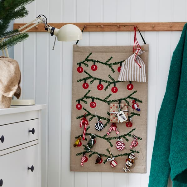 An einer Wand hängt ein Weihnachtssackerl und daran kleine Dekoartikel