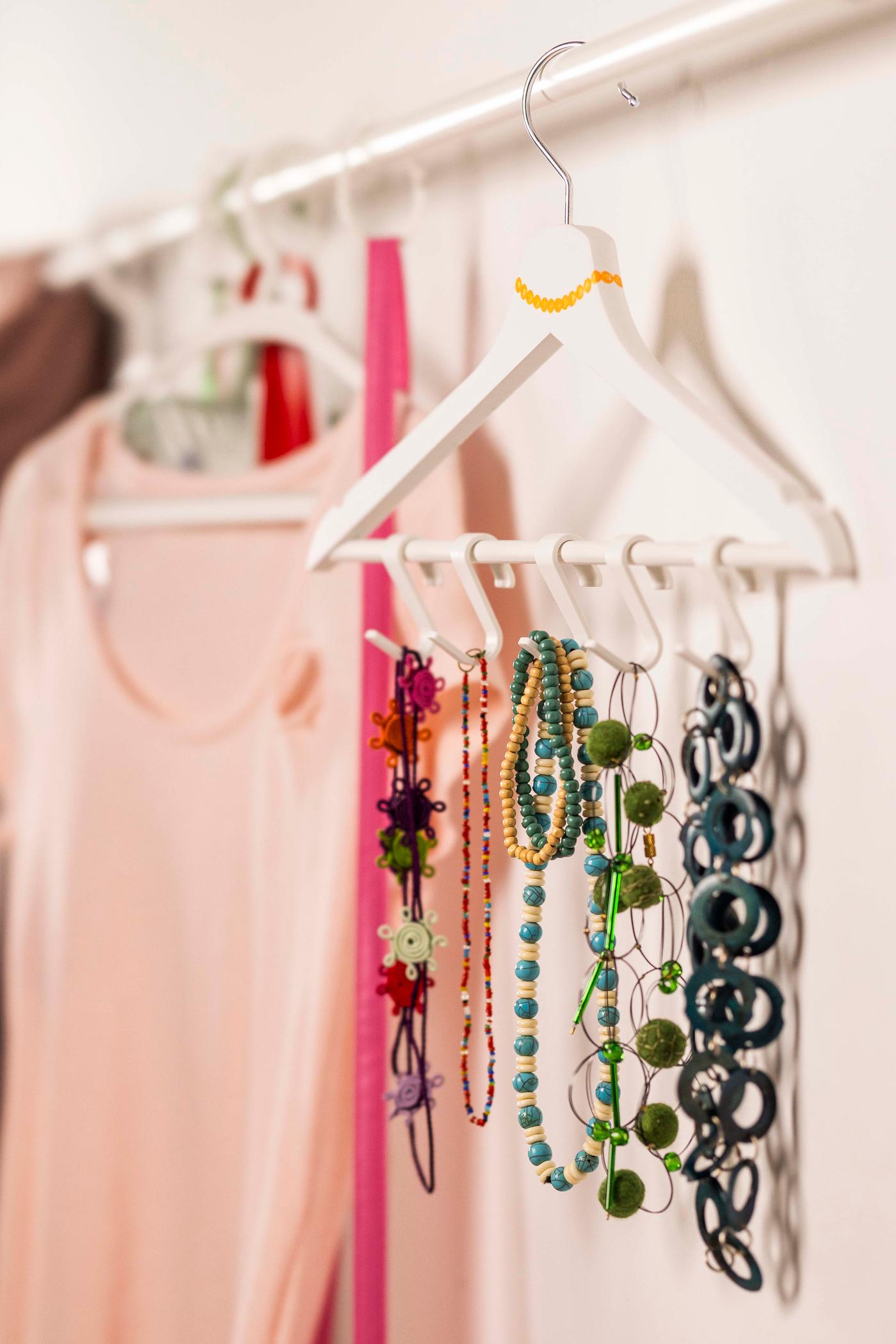 An einer Wand ist eine Kleiderstange befestigt und daran hängen rosane Kleider.