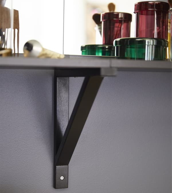 An EKBY LAIVA/EKBY VALTER shelf and wall bracket in black-brown mounted on the wall to create a bedroom vanity.