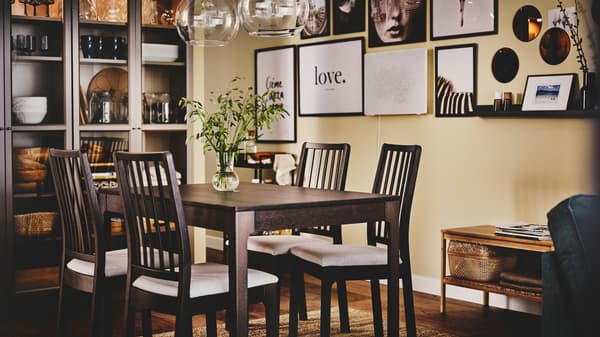 An EKEDALEN dining table and chairs sit in front of a gallery wall with a glass cabinet to the side containing kitchenware.