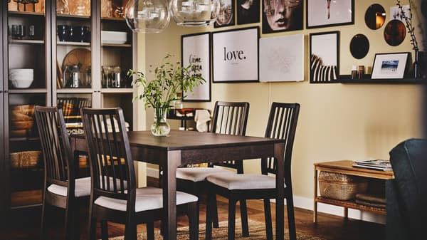 An EKEDALEN dining table and chairs sit in front of a gallery wall with a glass cabinet to the side containing kitchenware.