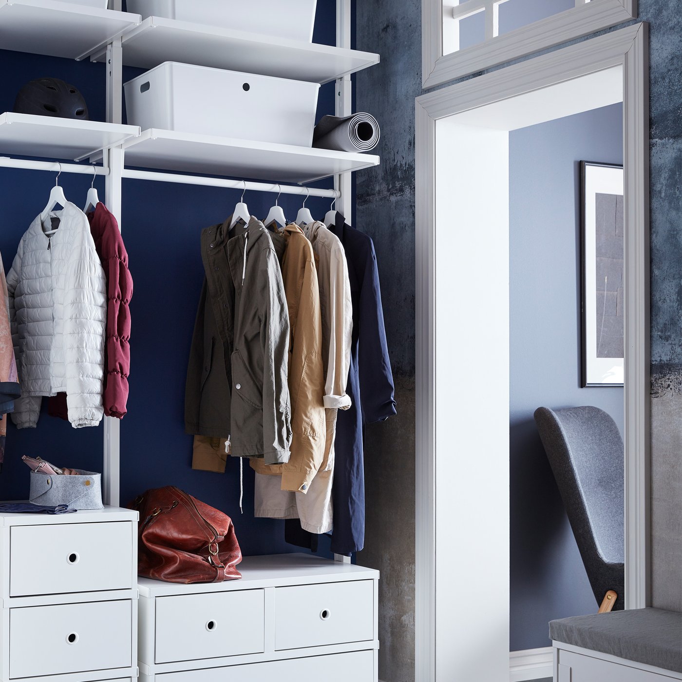 An ELVARLI storage system beside a doorway, with two drawer units, a hanging rail, and shelves holding KUGGIS boxes.