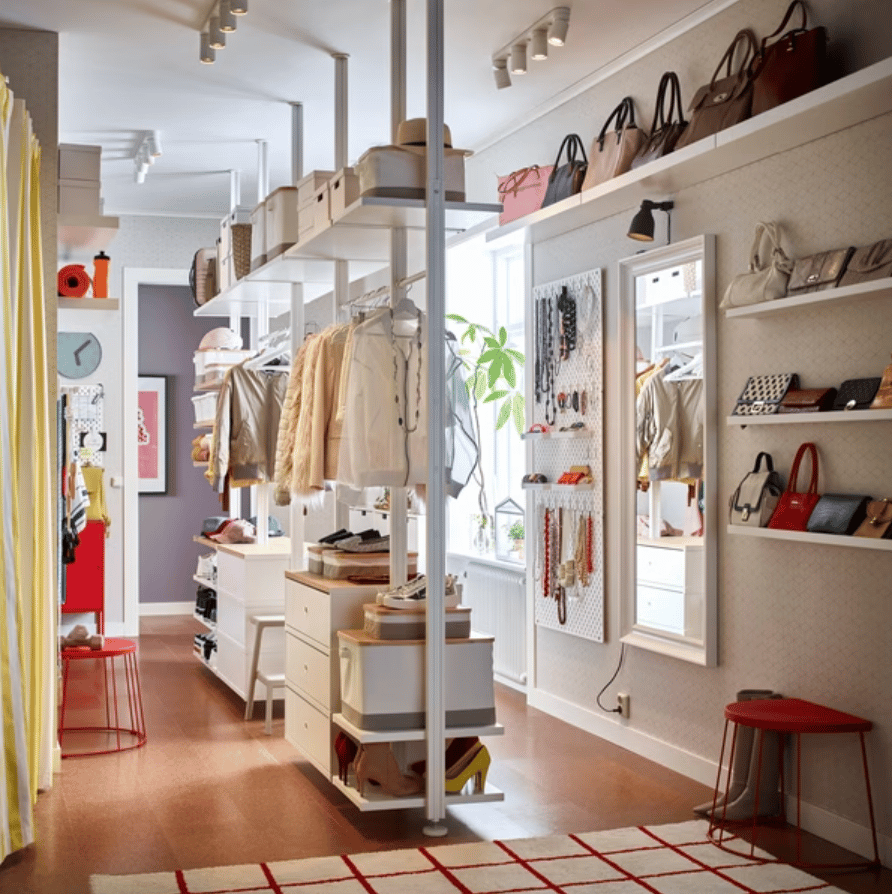 An ELVARLI wardrobe combination stands in a room holding clothes hanging on a rail, bags and other items.