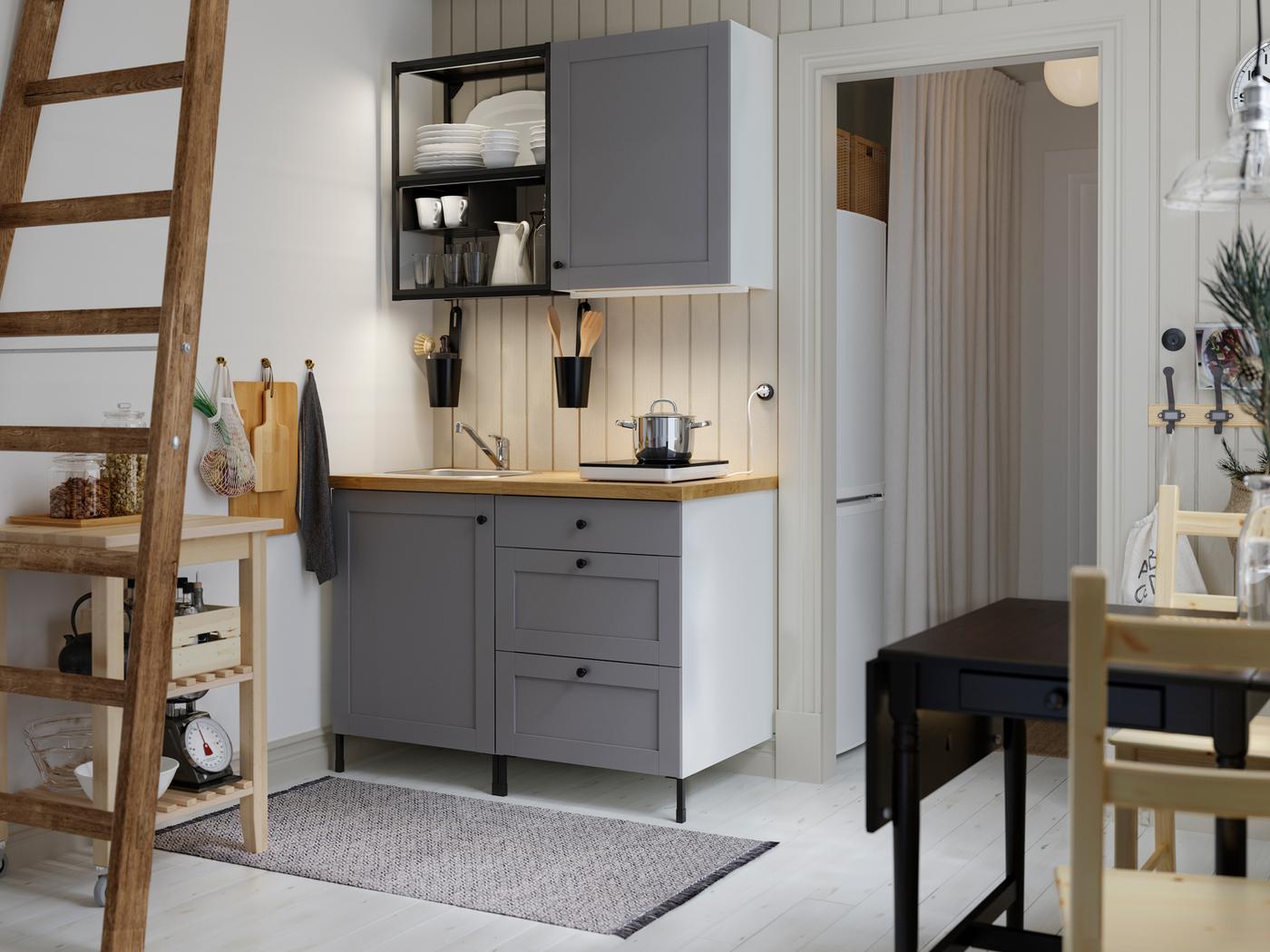An ENHET kitchen in anthracite and grey with a drop table in black and brown and a BEKVÄM kitchen trolley in birch.