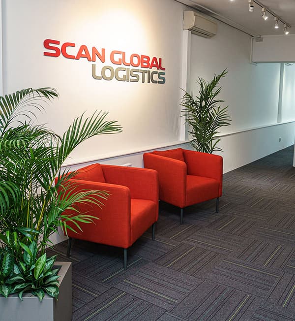 An entrance area featuring two red armchairs with potted plants beside.