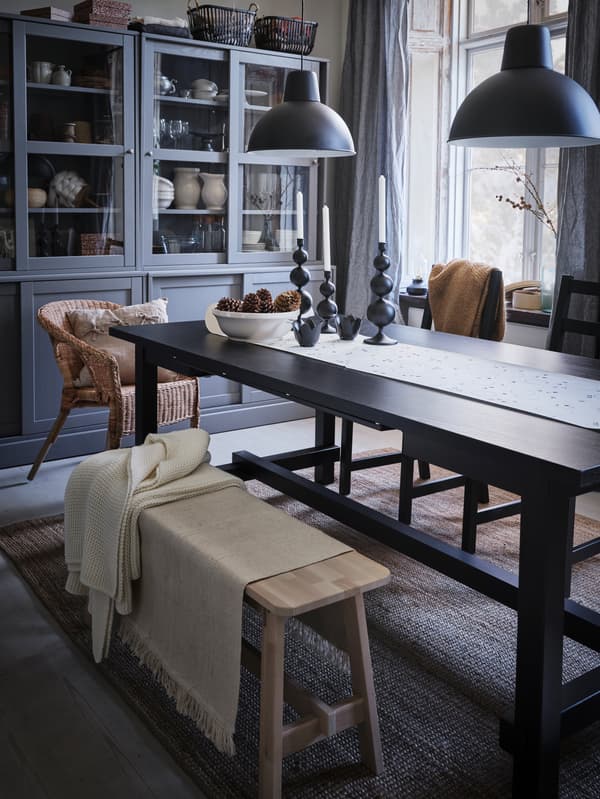 An extendable black NORDVIKEN table stands in a light-colored room, set ready for the festive meal to come.