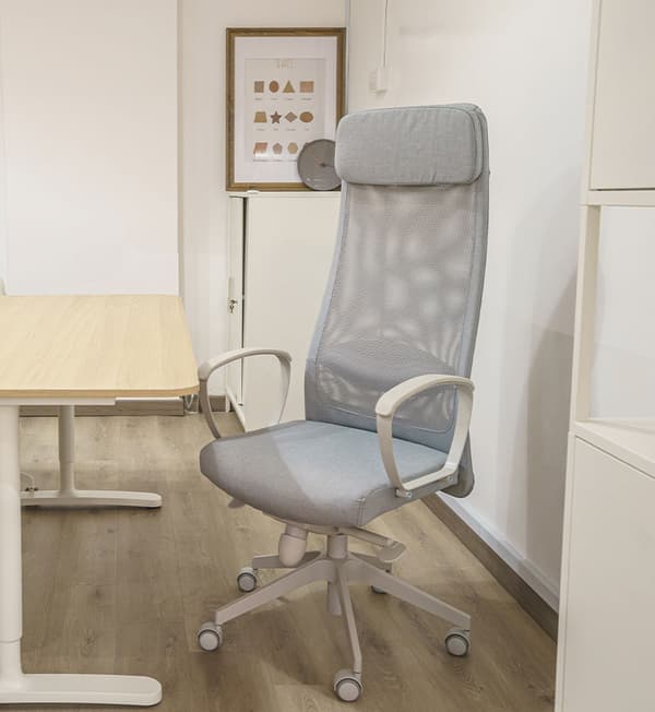 An grey ergonomic chair is placed behind the wooden desk.