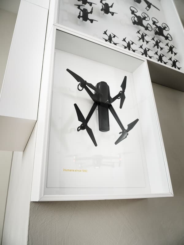 An IKEA ART EVENT 2021 wall piece with a black drone in a white frame; a second wall piece with drones is above it.
