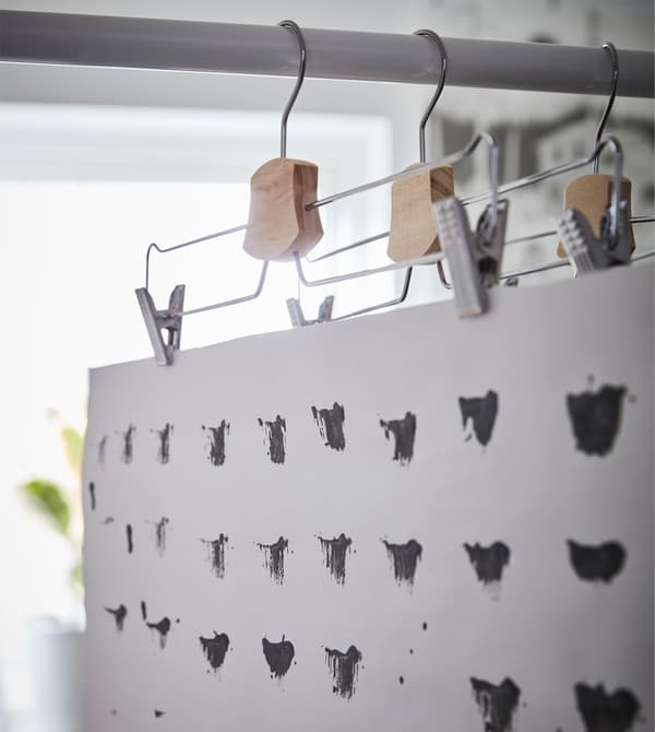 An IKEA BUMERANG trouser/skirt hanger displaying a black and white print for decoration in a dorm room.