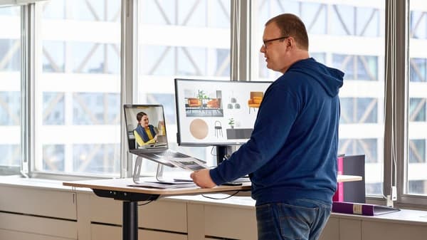 An IKEA Business Network customer is standing at a standing desk and making a video call with an IKEA employee.