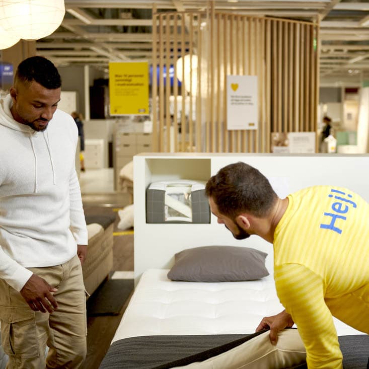 An IKEA co-worker advising two customers in the mattress studio.