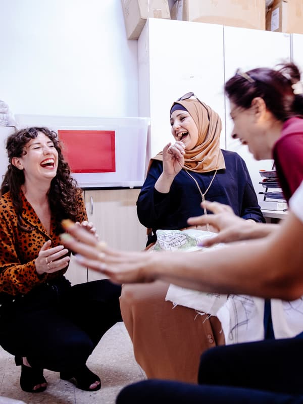 An IKEA co-worker and artisans from the Jordan River Foundation enjoy a laugh at a designer workshop.