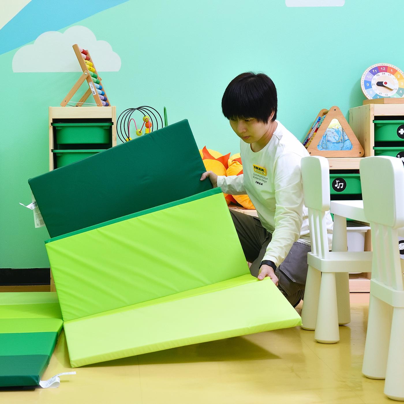 An IKEA co-worker arranges a PLUFSIG gym playmat in a kindergarten room.