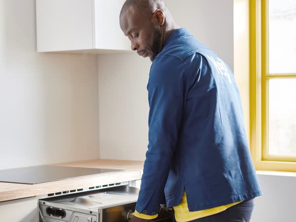An IKEA co-worker connecting an electrical appliance in a kitchen.