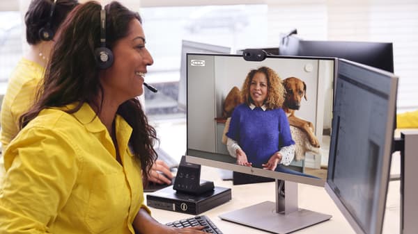 An IKEA co-worker has a headset on with a yellow shirt on and is speaking to a customer virtually on the computer