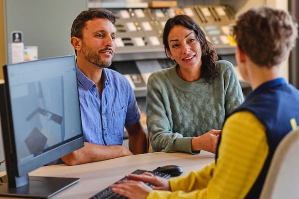 An IKEA co-worker helping two customers.
