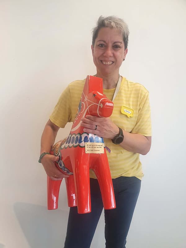 An IKEA co-worker holding a red Dala horse