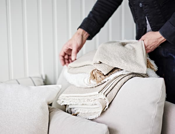 An IKEA co-worker holding up fabric samples in front of a sofa.